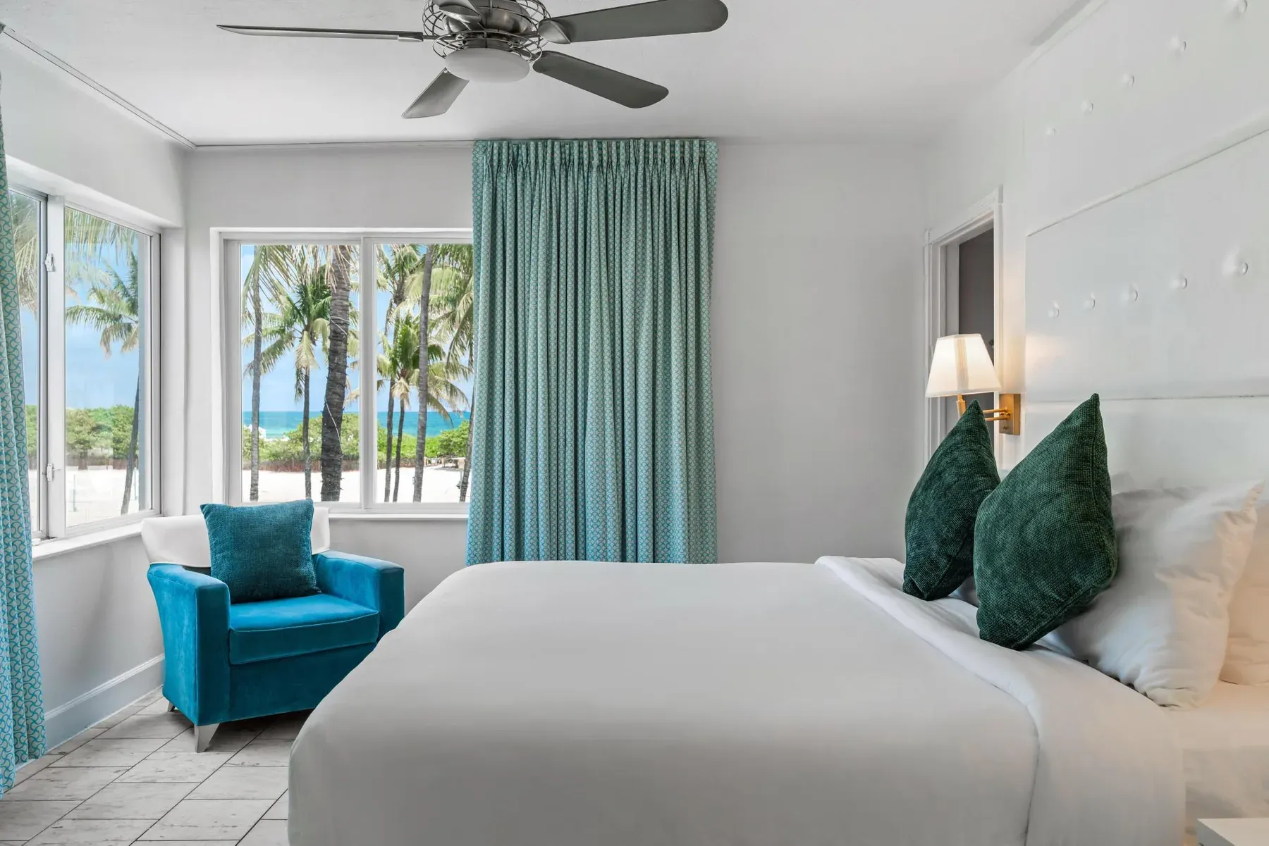 Ocean Front Room, king bed beside bay windows looking out to palms and the Atlantic