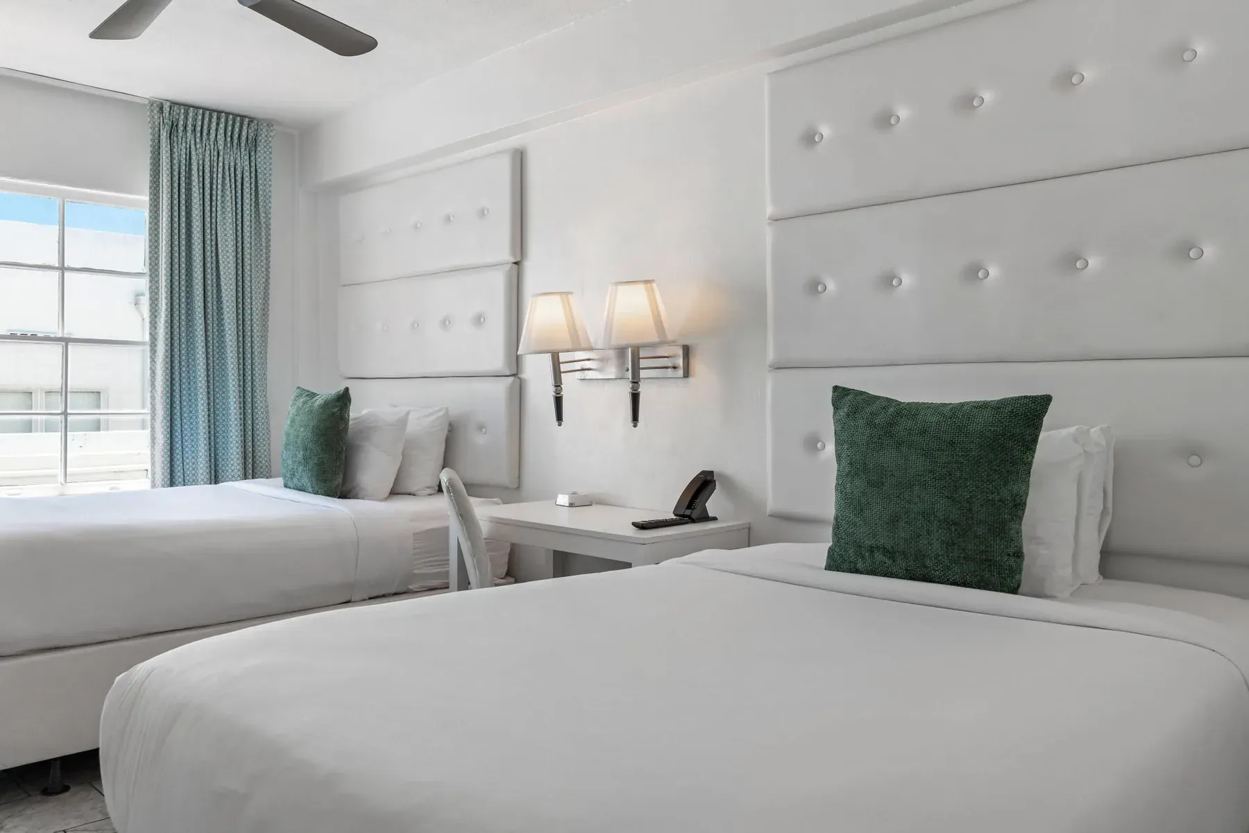 The two beds in daylight, teal curtains drawn back from the window