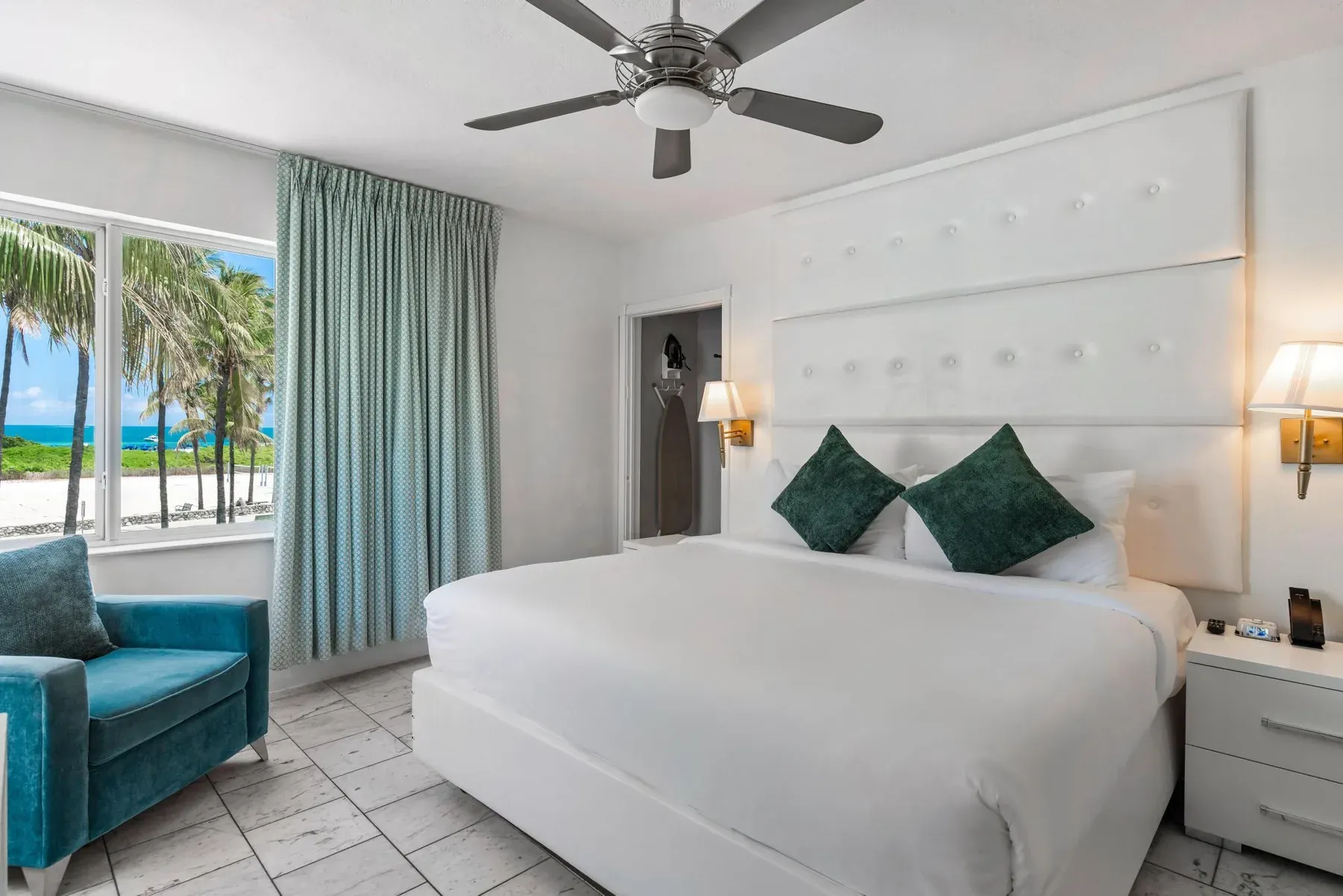 Bedside detail, the teal armchair and the windows over Ocean Drive