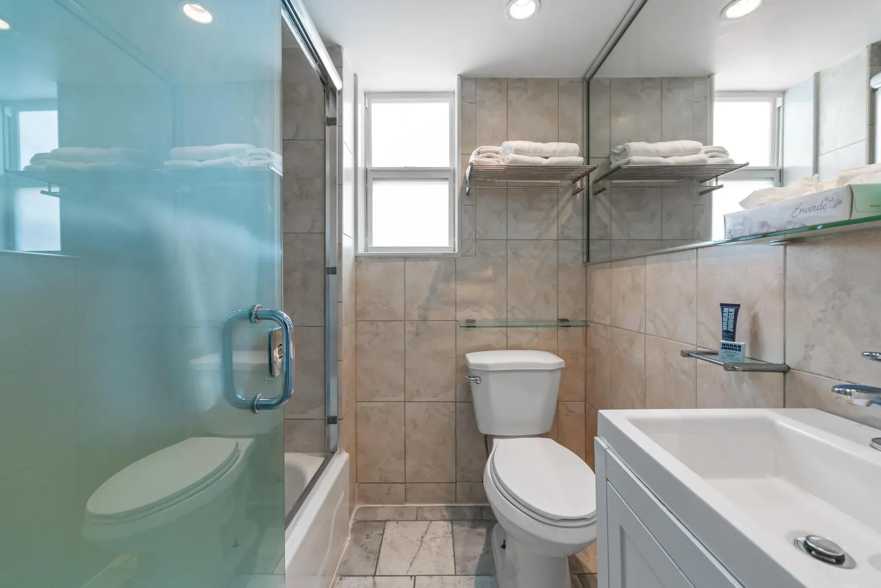 The bathroom, glass shower screen and stacked towels