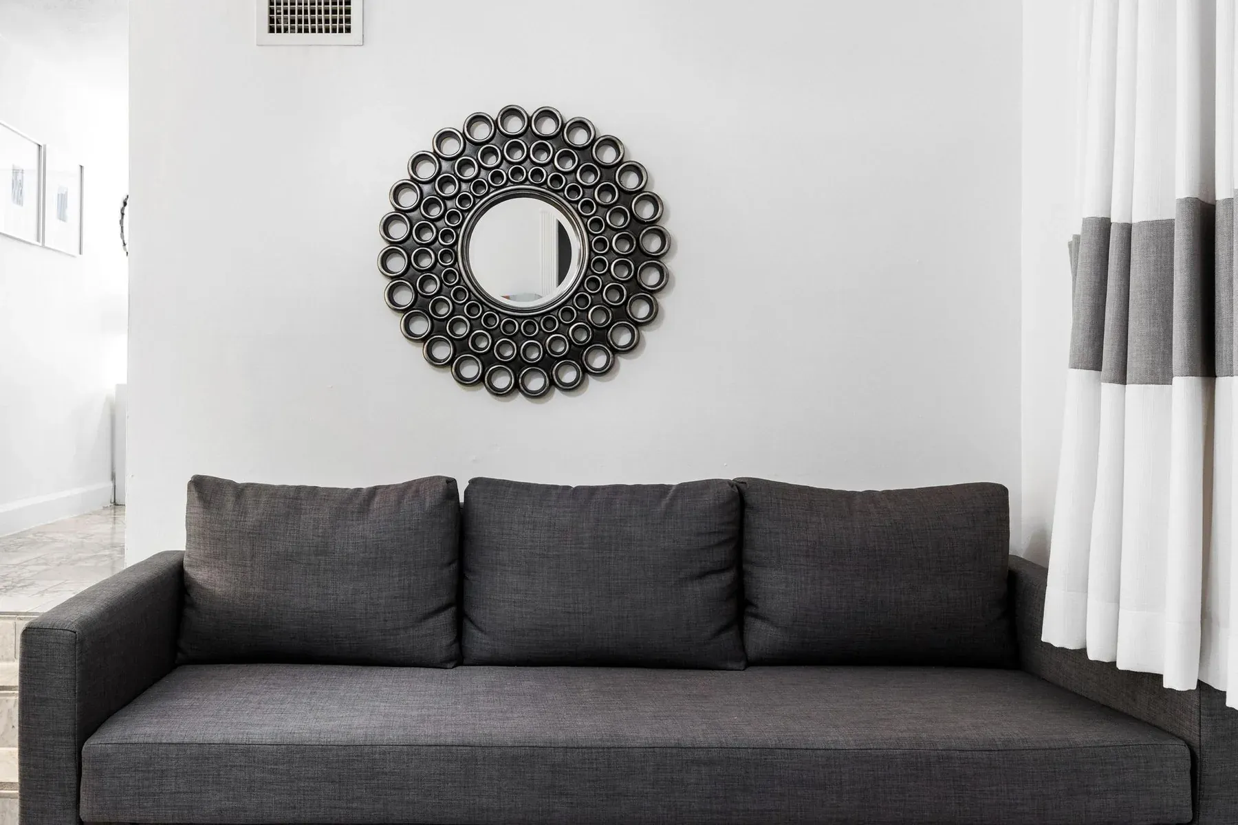 The living room sofa beneath a Deco sunburst mirror